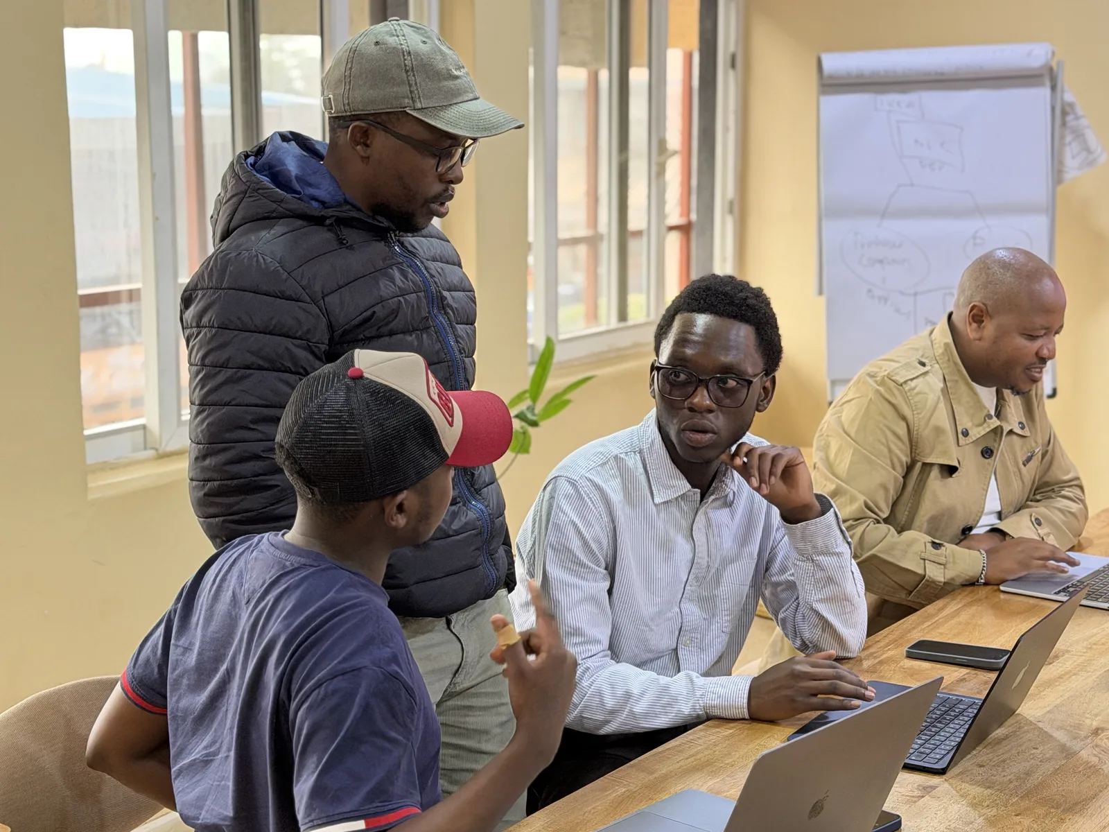 Vier collega's van Data XL werken samen een vraagstuk door aan de tafel in het kantoor in Nairobi